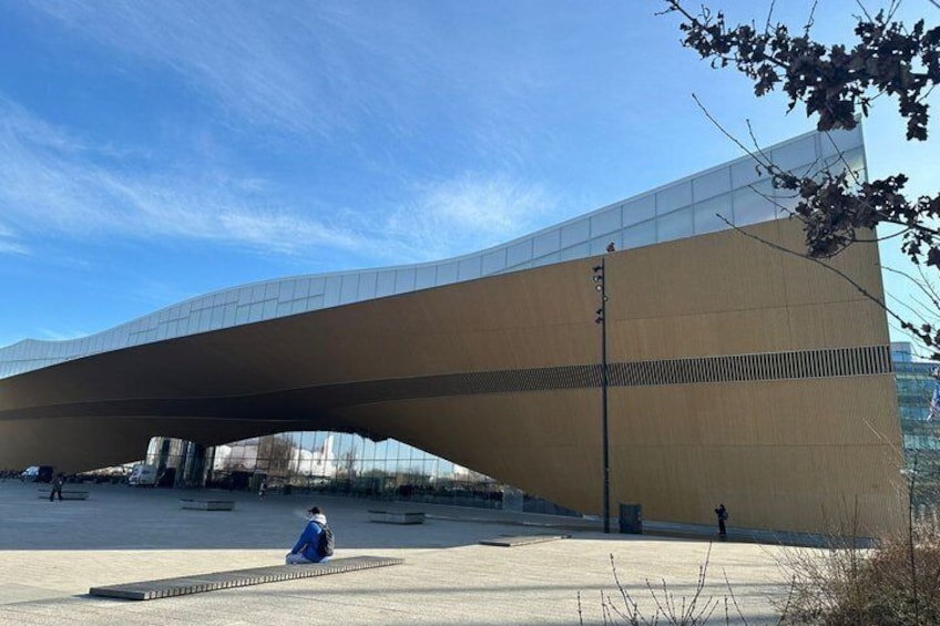 A modern architectural structure with a curved roof and a clear sky. 2