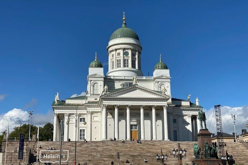 A large white building with a green dome and columns, located in a city square. 4