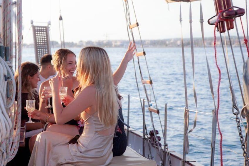 A group of people on a sailboat with a city skyline in the background. 1