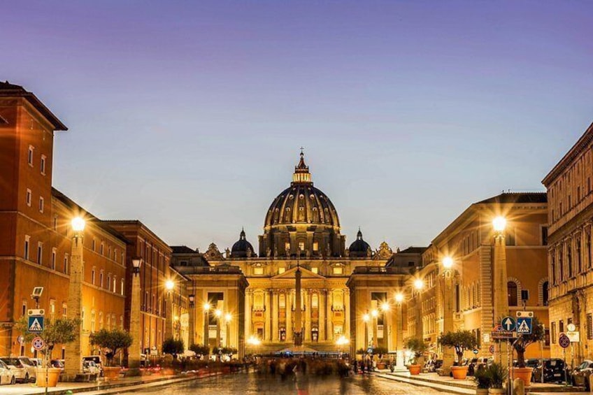 A grand building with a large dome, surrounded by illuminated street lamps and other buildings. 4