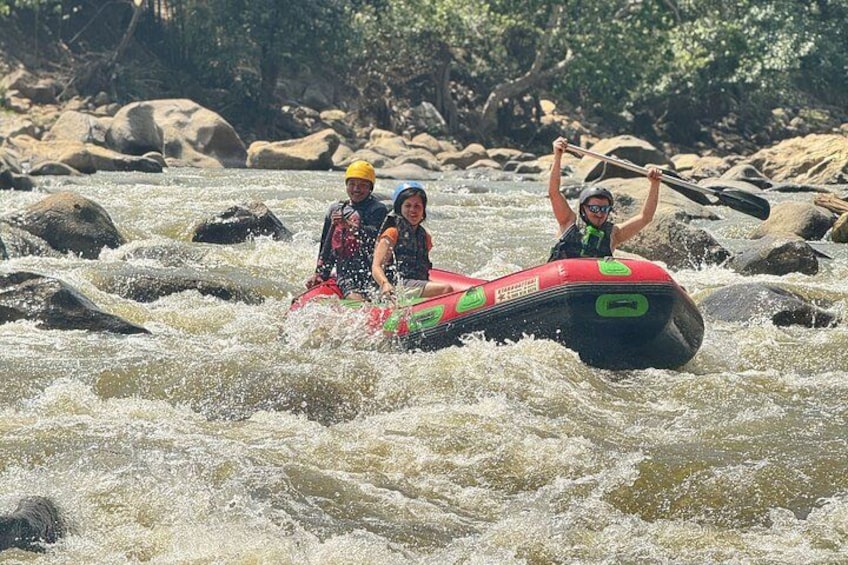 Dos personas en una balsa hinchable roja navegando un río con rápidos. 2