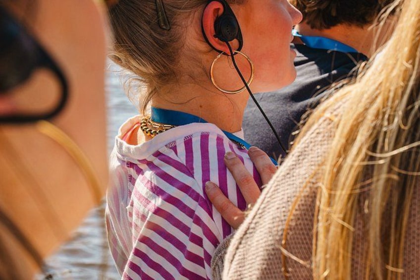 A person wearing a striped shirt and a necklace, with a microphone in their ear. 2