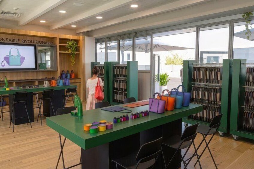 Et bibliotek med grønne borde, farverige tasker og reoler med bøger. 3