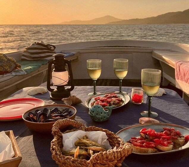 A table set with food and drinks on a boat with a view of the sea and mountains. 2