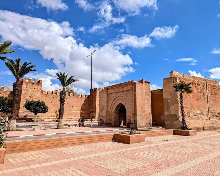 A historic fort with a large archway, palm trees, and a clear blue sky. 3