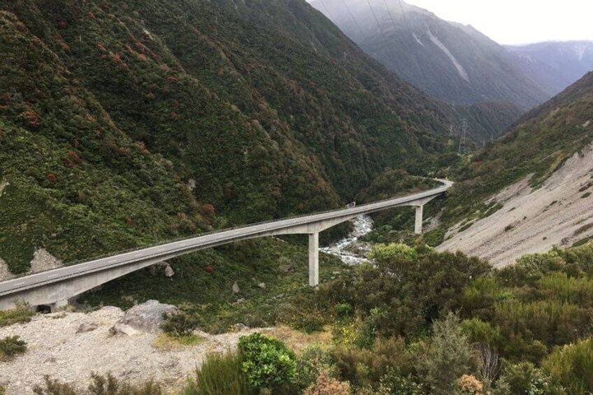 A bridge spanning a valley with steep hills and dense vegetation. 4
