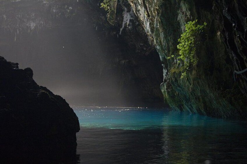 L'apertura di una grotta si affaccia su un mare turchese, con formazioni rocciose e vegetazione. 4