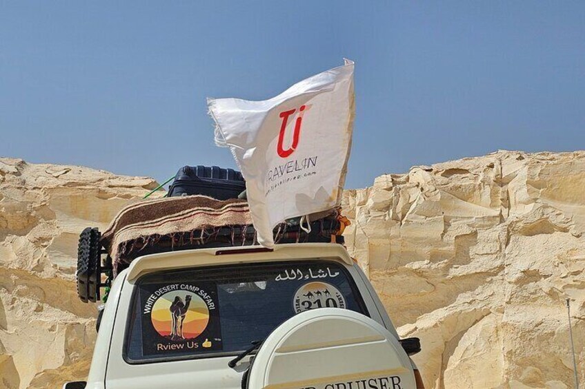 Un véhicule arborant un drapeau et le logo d’un campement dans le désert. 3