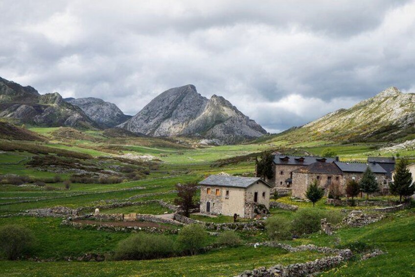 A rural landscape with a stone house, green fields, and mountains in the background. 5