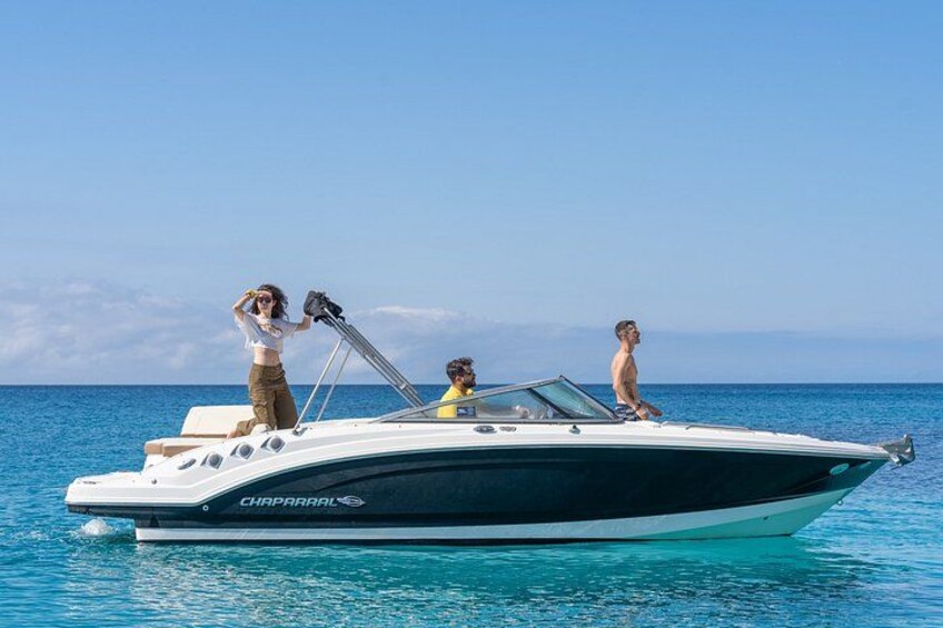 A boat with three people on it, a clear blue sky, and calm water. 1