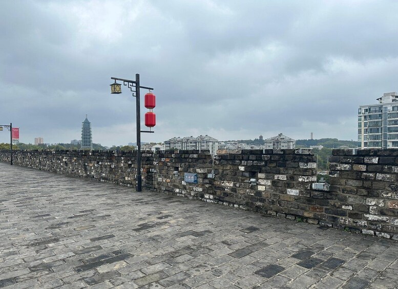 A stone wall with a lantern post and a pagoda in the background. 5