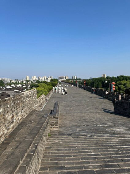 A stone pathway leading to a cityscape with modern buildings and a clear sky. 1