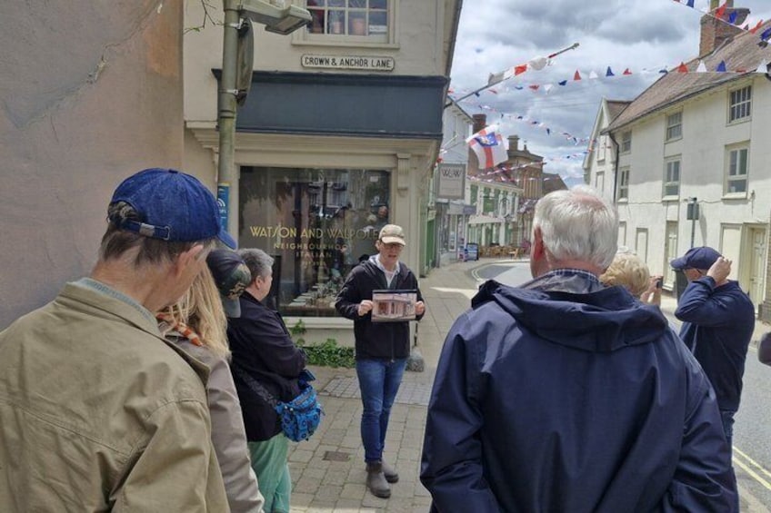 A group of people standing on a street, some looking at a person holding a sign. 1