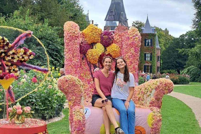 Eine Frau und ein Kind sitzen auf einem Blumenstuhl in einem Garten mit einer Burg im Hintergrund. 4