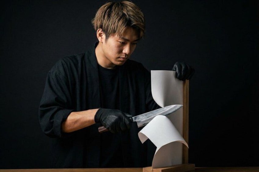 A person in black cutting paper on a wooden table. 1