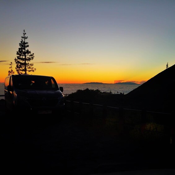 A vehicle parked on a road with a sunset in the background. 4