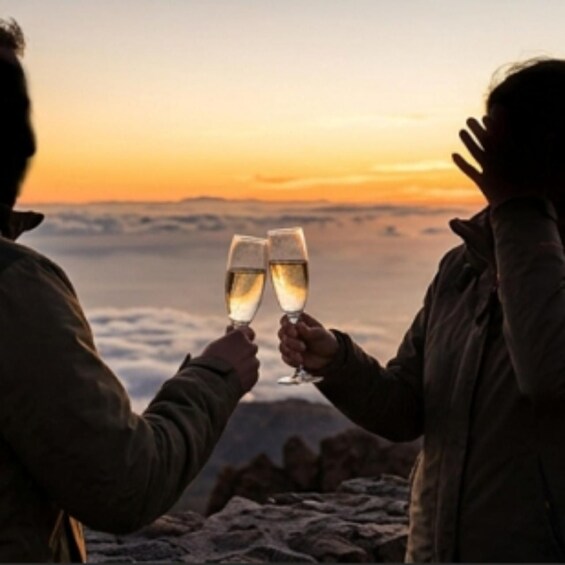 Two people toasting with champagne glasses against a sunset backdrop. 1