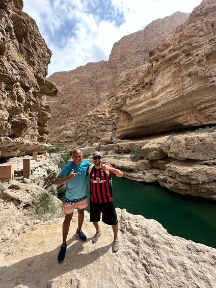 Two people standing on a rocky ledge with a river in the background. 3