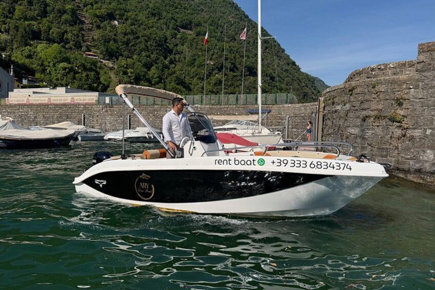 A white and black boat docked at a marina with a man standing on the deck. 4