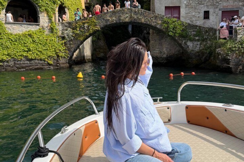 Une personne se trouve sur un bateau, avec un pont de pierre et de la verdure en arrière-plan. 2