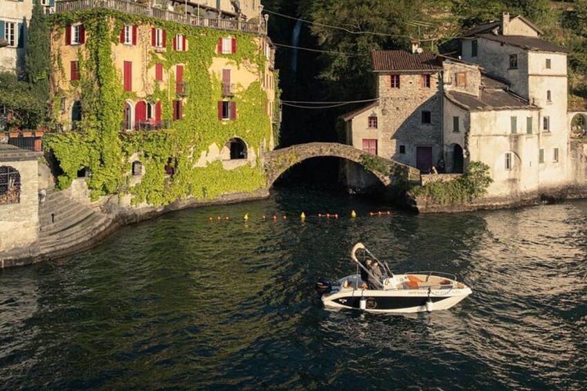 A boat on a river, a stone bridge, and buildings with red shutters and greenery. 3