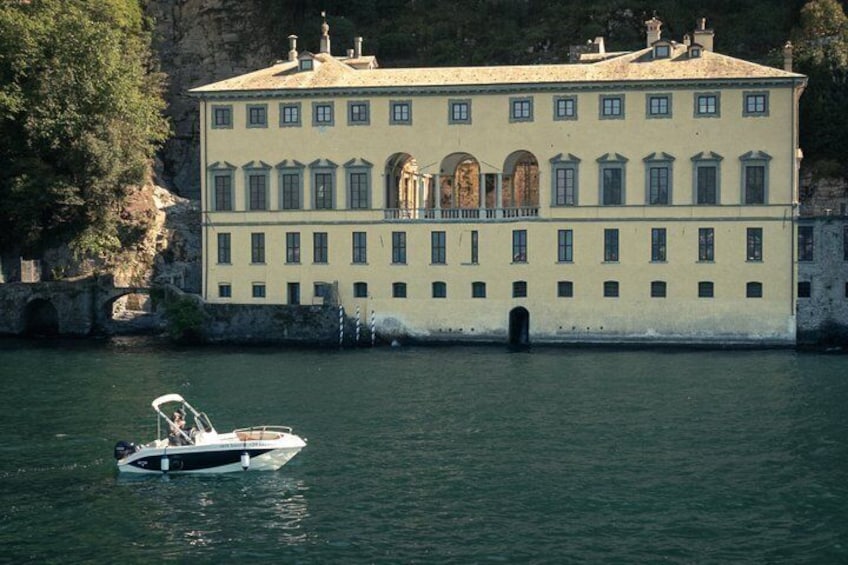 Un bâtiment historique situé au bord d’un lac paisible, avec un bateau en premier plan. 4