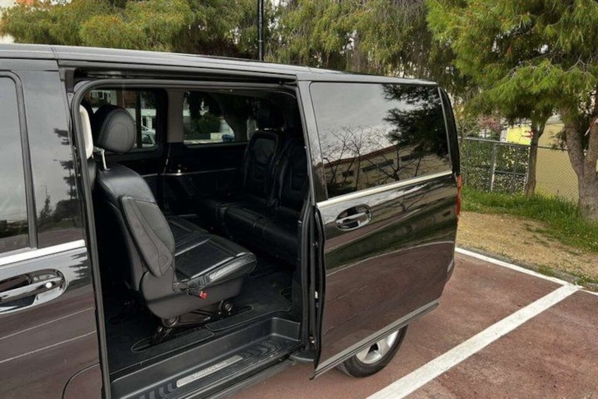 A black van parked in a parking lot with its door open, revealing the interior. 2