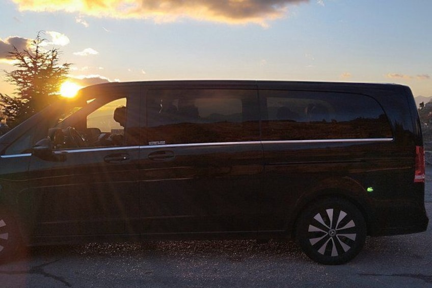 A black van parked on a road with the sun setting in the background. 3