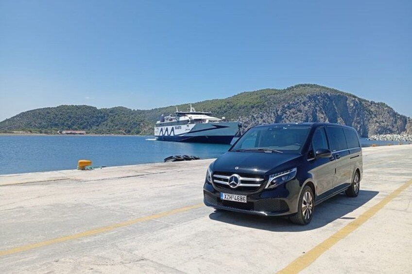 A Mercedes-Benz van parked on a concrete surface near a body of water with a boat in the background and a hilly landscape. 4