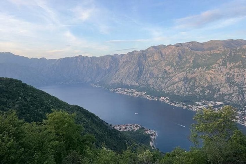 A mountainous landscape with a lake, dense greenery, and a distant town. 5