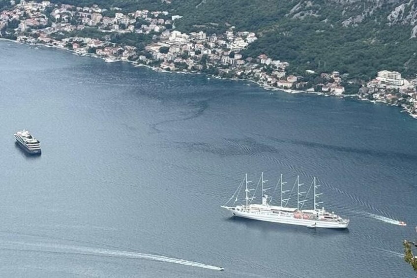 A large sailing ship and a smaller vessel in a coastal area with a town in the background. 4