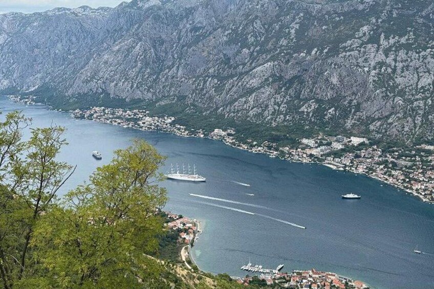 A coastal town with mountains in the background, a clear blue sea, and several boats. 3