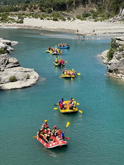 A group of people kayaking on a river surrounded by rocky terrain and greenery. 4