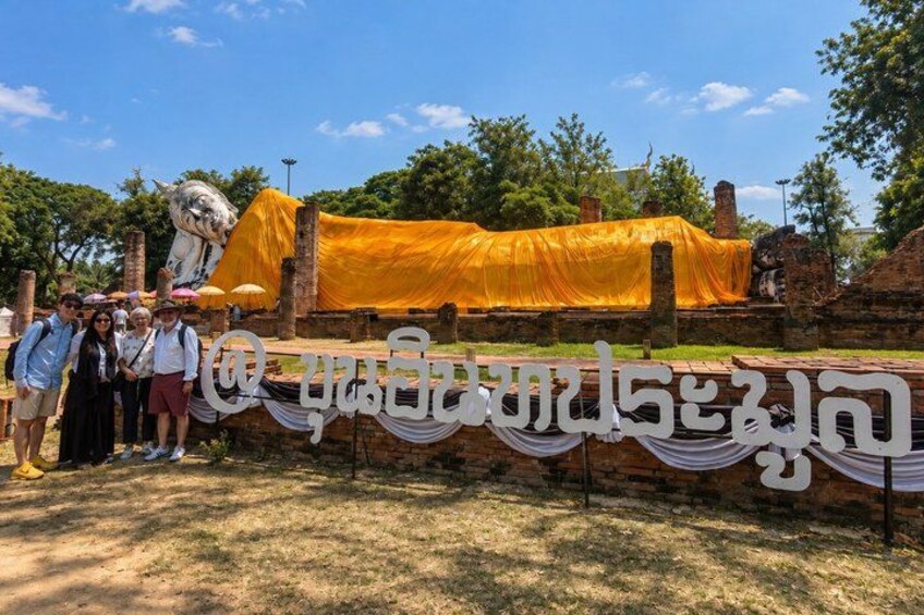 A historical site with a large statue, a yellow cloth covering part of the structure, and a banner with text. 3