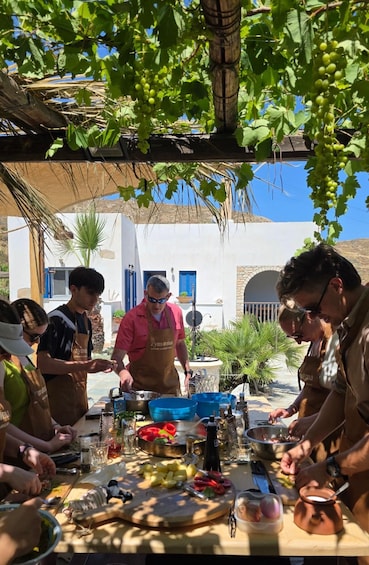 A group of people preparing food outdoors with a table full of ingredients and cooking utensils. 5