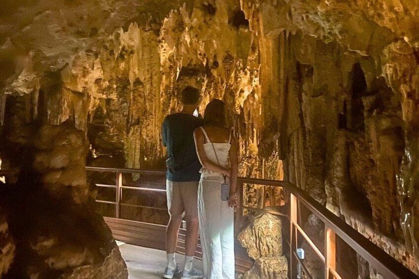 A couple standing on a bridge inside a cave with stalactites. 1