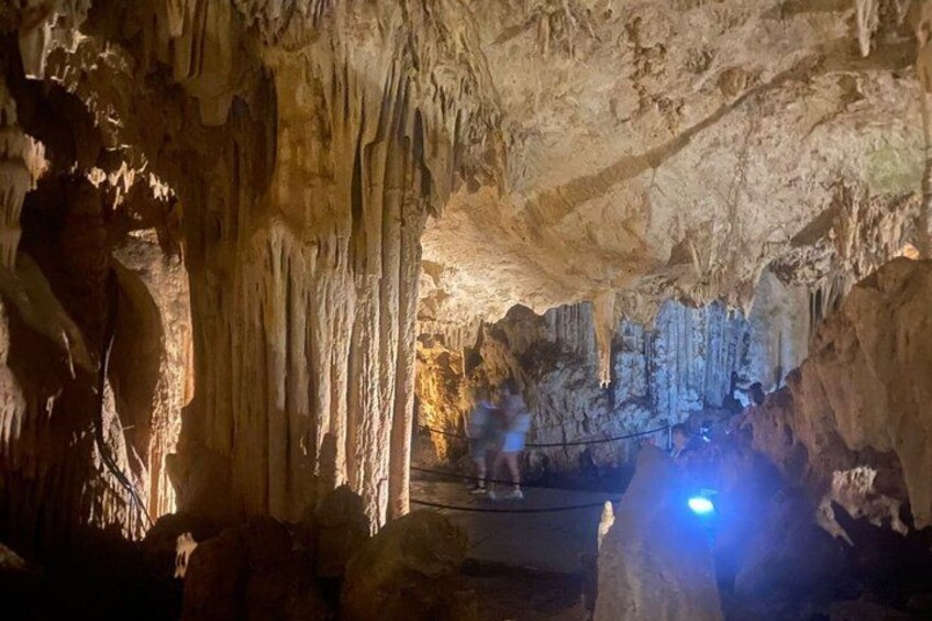 A cave interior with stalactites and stalagmites, a rope for safety, and a blue light source. 4