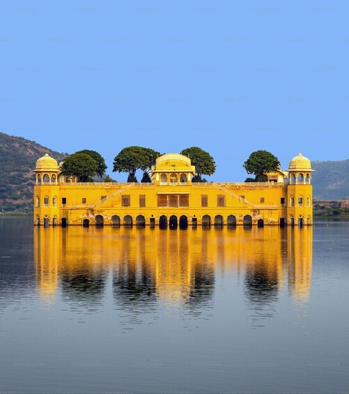 A yellow building with domes and arched windows, surrounded by water and trees. 2