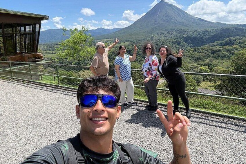 A group of people on a viewing platform with a volcano in the background. 1