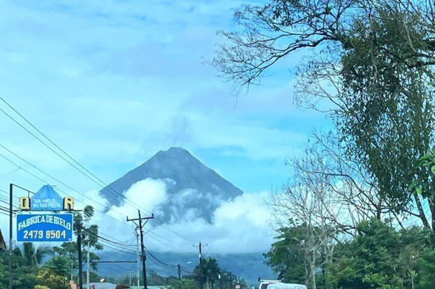 A mountain with clouds, a road sign, and power lines. 3
