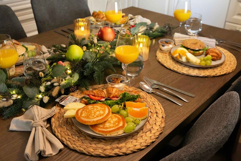 A breakfast setting with plates of food, glasses of orange juice, and candles. 4