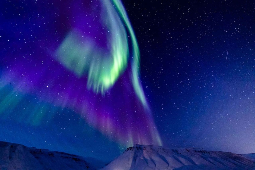 The Northern Lights over a snowy mountain landscape. 4