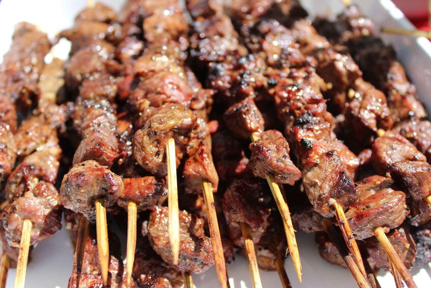 Vartaassa grillattua lihaa, todennäköisesti kebabia, valkoisella lautasella. 3