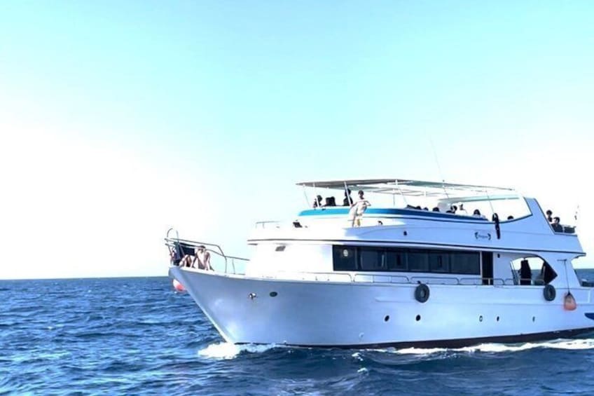 Un yate blanco con varias cubiertas y pasajeros a bordo, navegando en el océano. 3