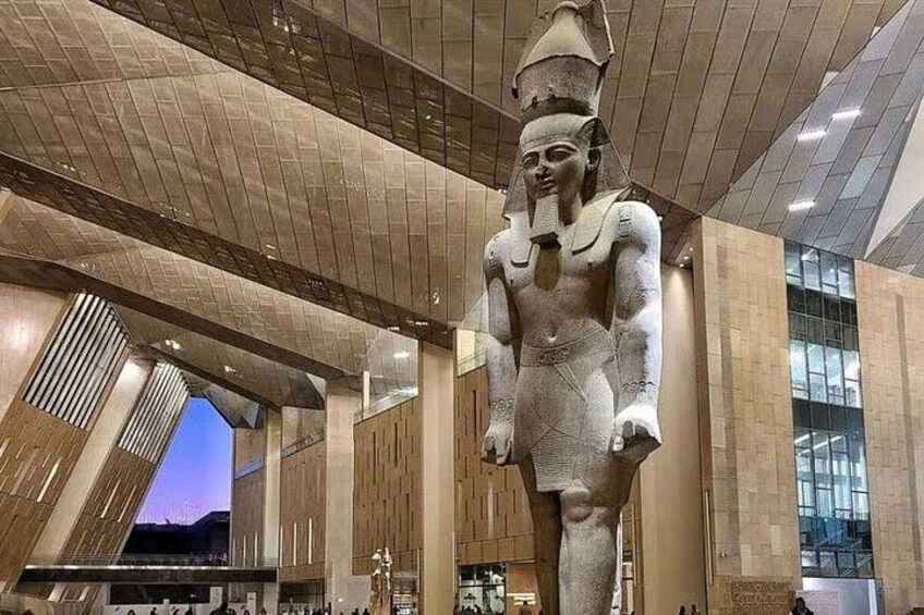 Una gran estatua egipcia antigua en un edificio moderno con techo alto y ventanas amplias. 5