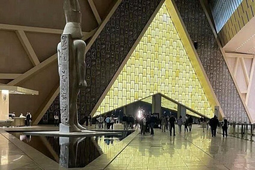 Un edificio moderno con una gran estructura en forma de pirámide y una estatua al frente. 3