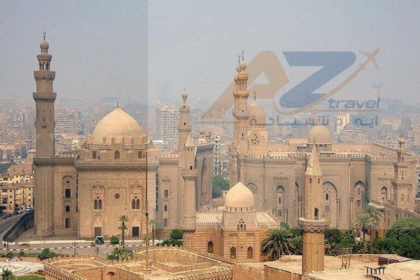 A large mosque with multiple domes and minarets, surrounded by urban buildings and palm trees. 4
