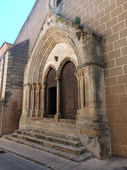 A stone church entrance with arched doors and steps leading up to it. 1