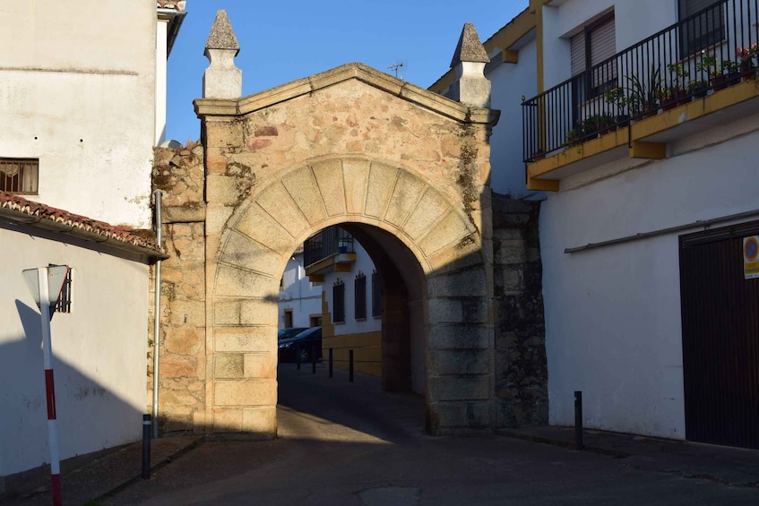 A stone archway in an urban setting with buildings on either side. 2