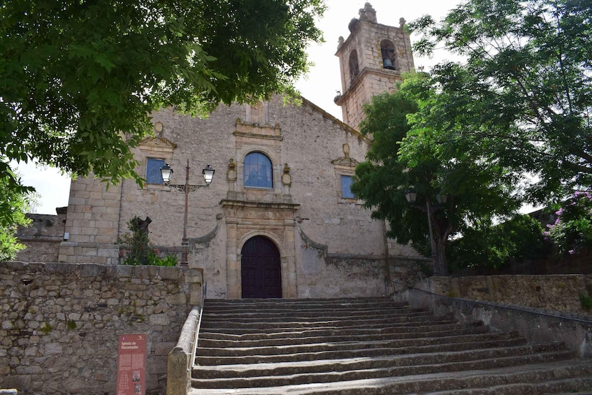 A historic church with a bell tower, stone steps leading up to the entrance, and surrounding greenery. 3